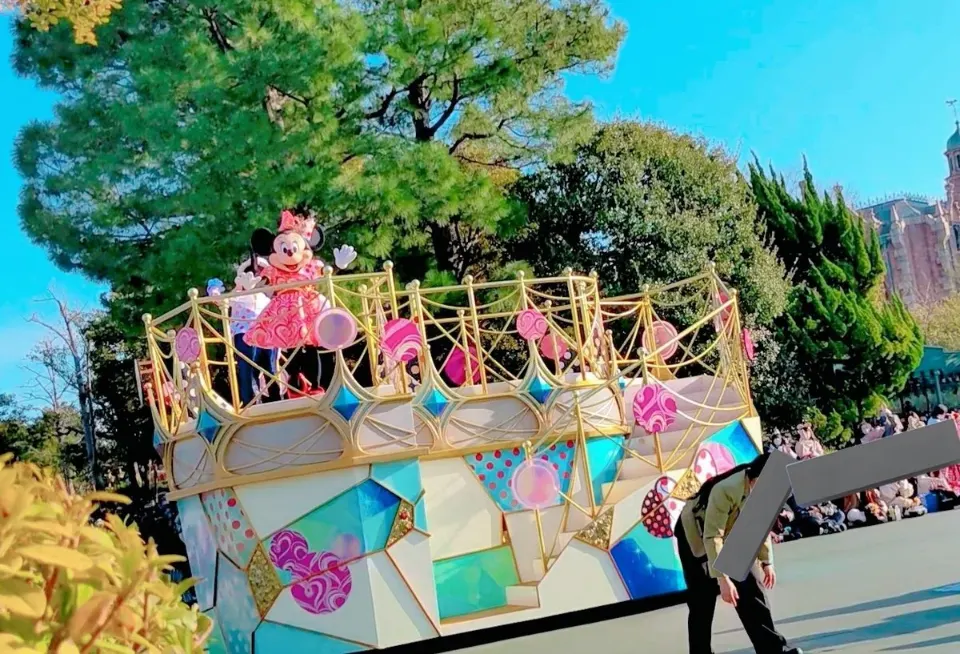 ディズニーランドの屋外で、華やかなフロートが進むパレード
