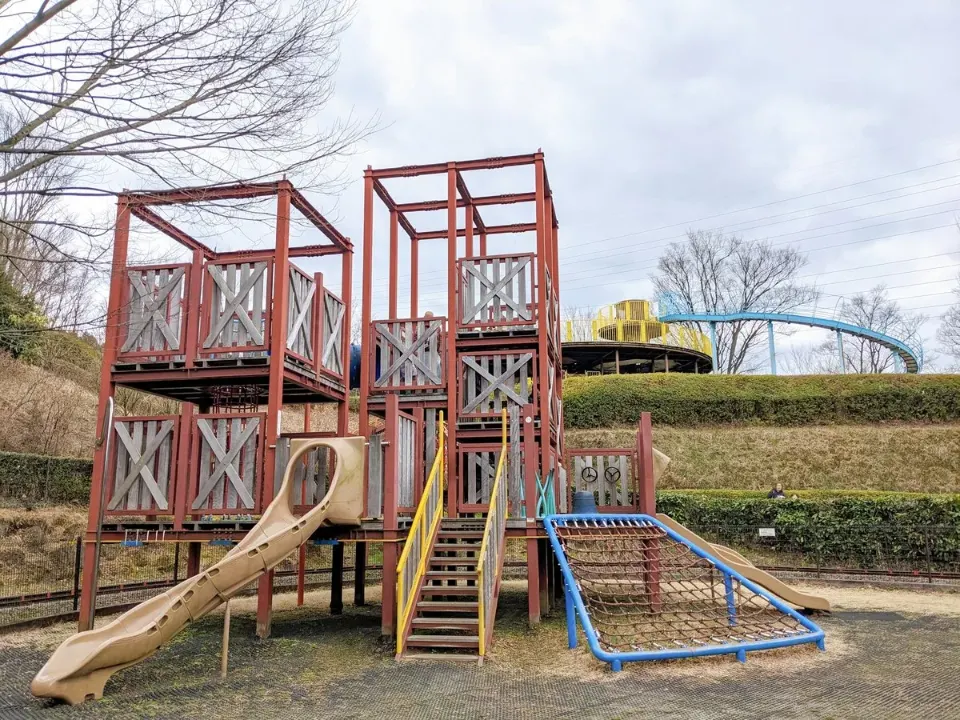赤い塔とロープの橋がつながる木製遊具