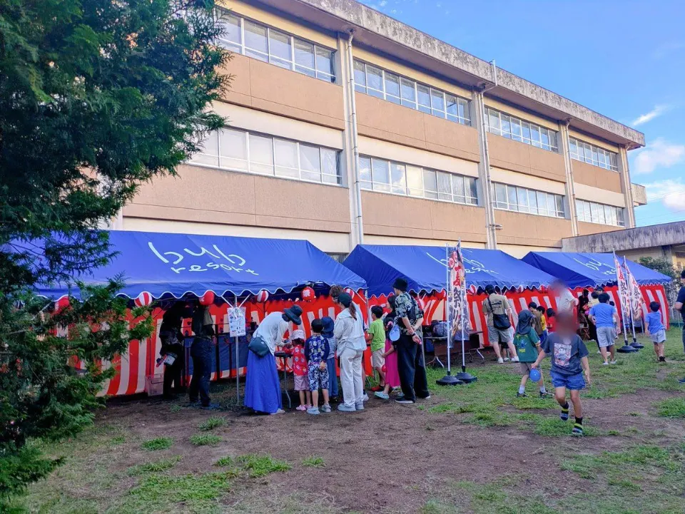 校舎前に並ぶ夏祭りの屋台とクルー