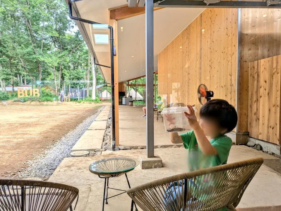 緑を眺められるテラスの椅子でくつろぐ子ども