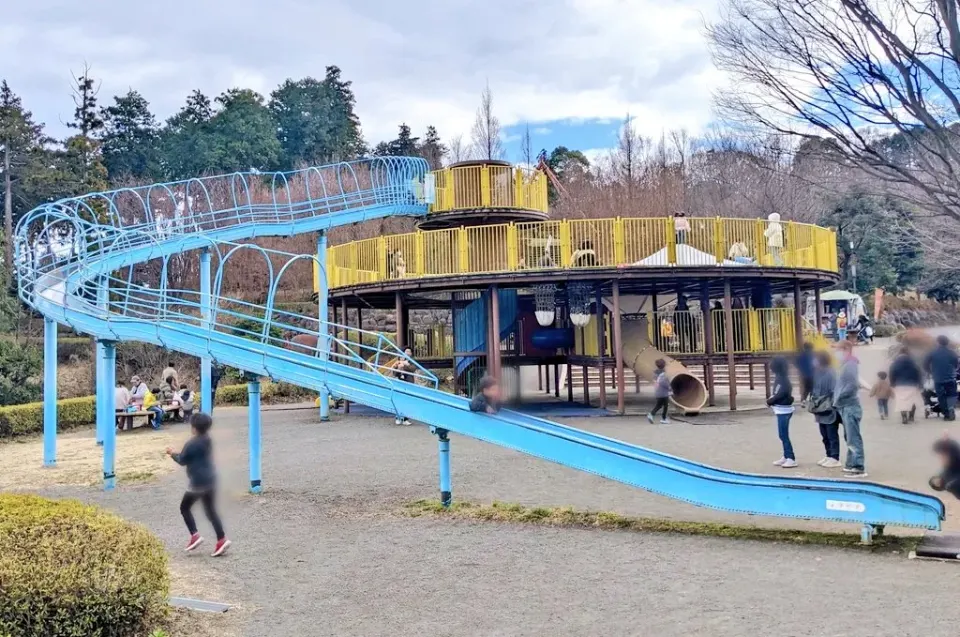 黄色い展望デッキを囲む長い青い滑り台
