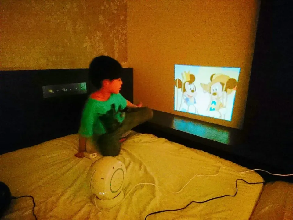 客室の壁に映した絵本を楽しむ子ども
