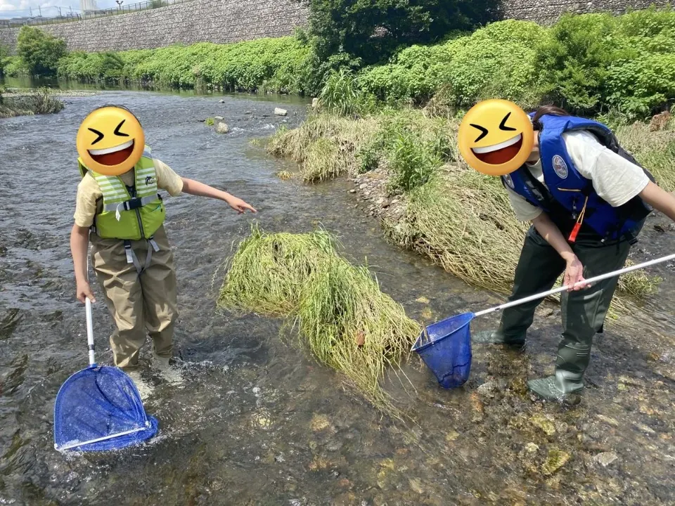網を持って川を歩く親子