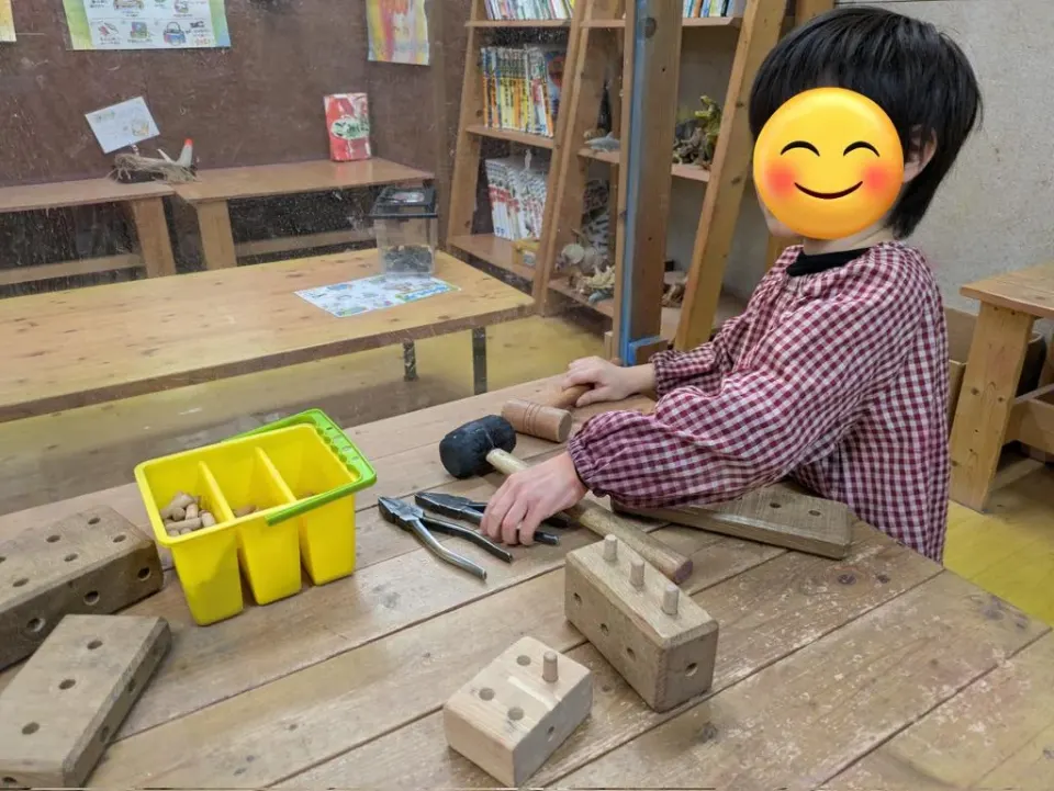 工具のある作業台で制作する子ども