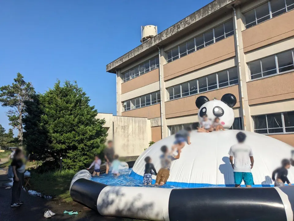 校舎前のパンダ型プールで遊ぶ子どもたち